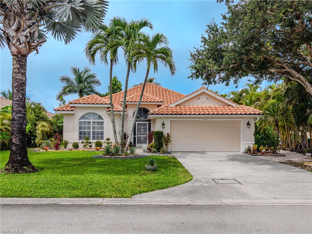 Mediterranean-style architecture with a terracotta tile roof, arched windows, and a two-car garage