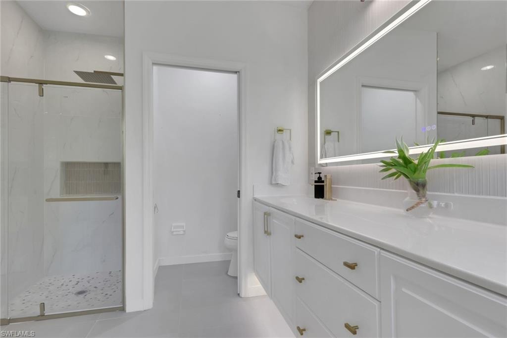 Walk-in shower with glass enclosure, rain showerhead, and tiled niche