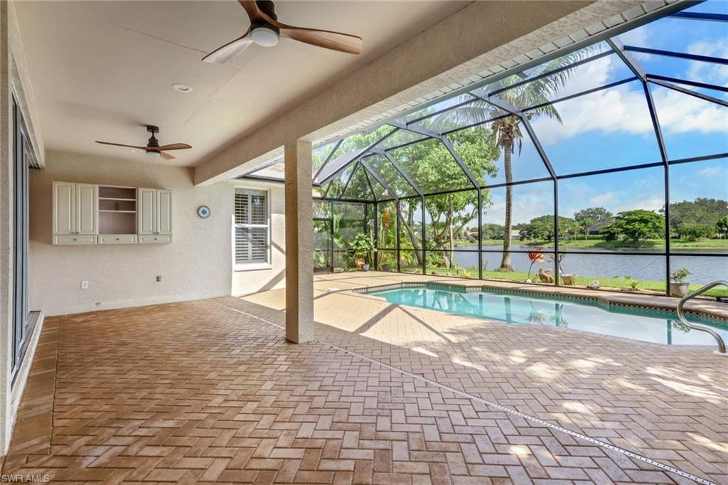 Screened-in outdoor living area with a rectangular swimming pool, herringbone brick-finish flooring, built-in cabinetry, and ceiling fans
