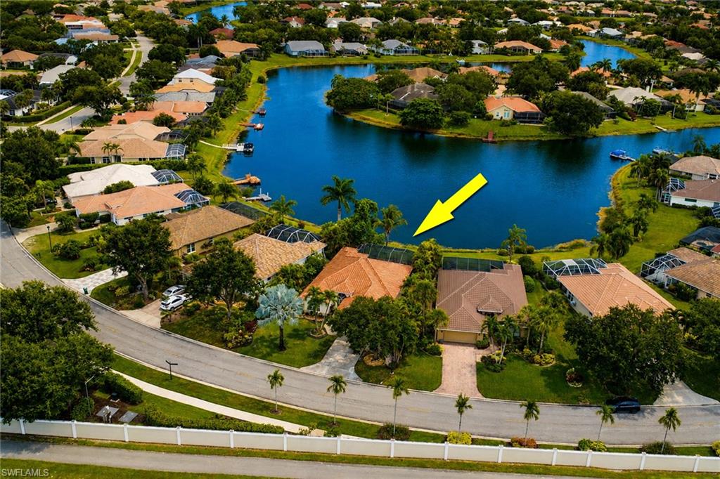 Waterfront property with a lush green lawn, mature trees, and a paved driveway