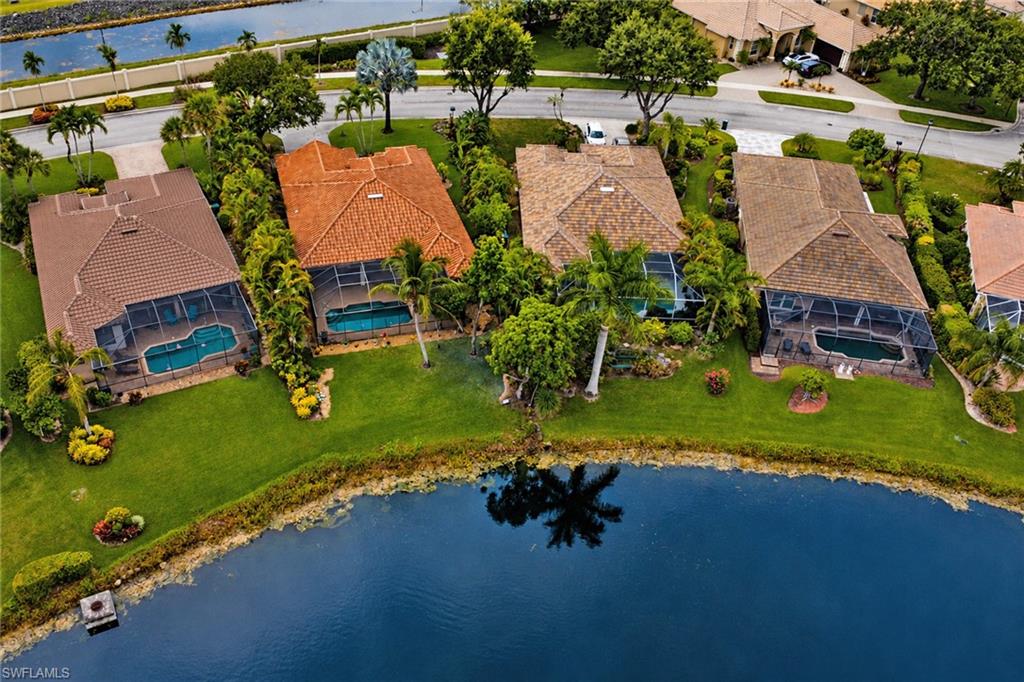 Waterfront property with private screened pool, manicured lawn, and mature landscaping