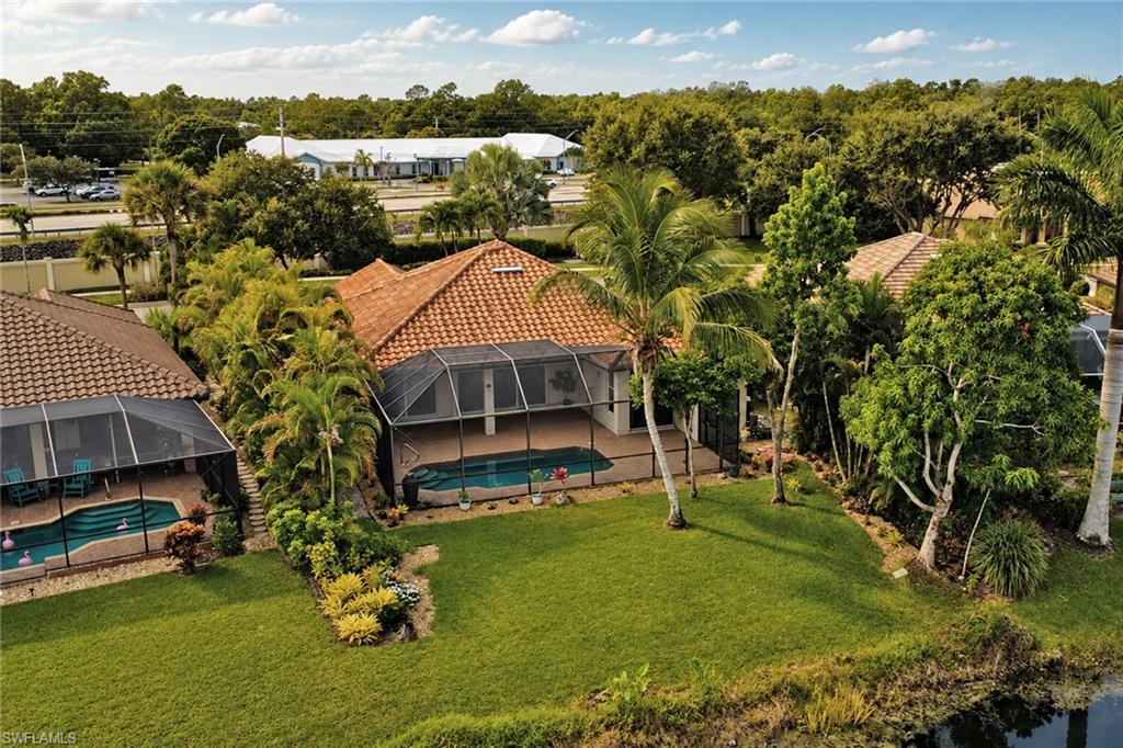 Terracotta tile roof, screened enclosure with a swimming pool, verdant lawn, mature palm trees, and established landscaping