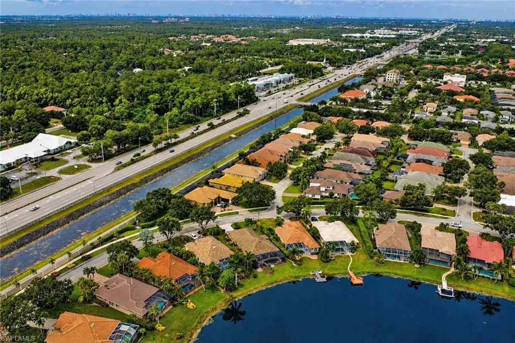 Aerial perspective showcasing a residential community with mature landscaping, a prominent waterway, and a main thoroughfare