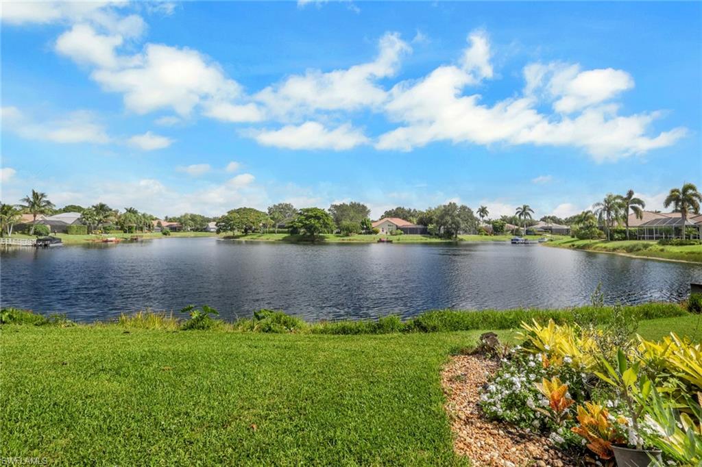 Expansive rear yard featuring a large body of water, manicured lawn, and mature landscaping