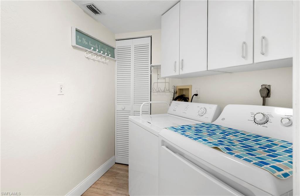 Laundry area with cabinet space, light wood-type flooring, and independent washer and dryer