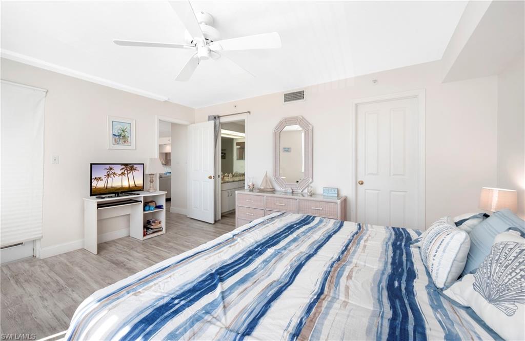 Bedroom with wood finished floors, a ceiling fan, and ensuite bathroom