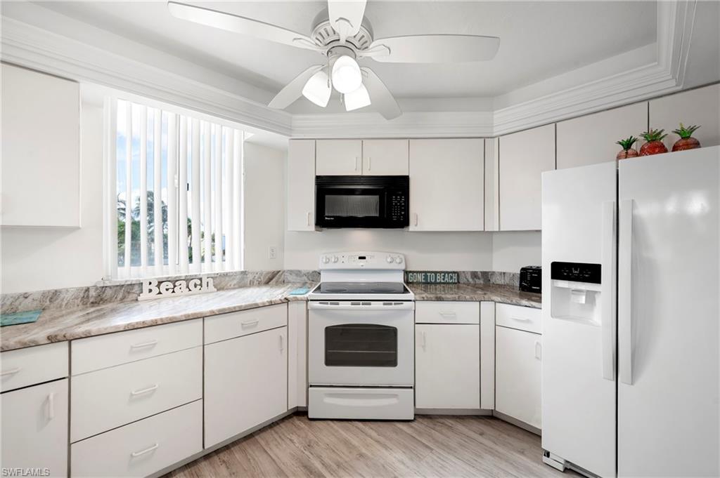Kitchen featuring white appliances, white cabinets, light wood finished floors, and ceiling fan