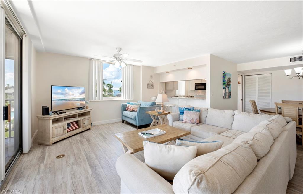 Living area with light wood-type flooring, a chandelier, and a ceiling fan