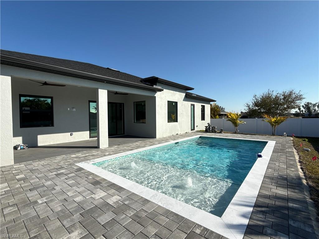 Rectangular swimming pool with integrated water features, bordered by light-colored coping