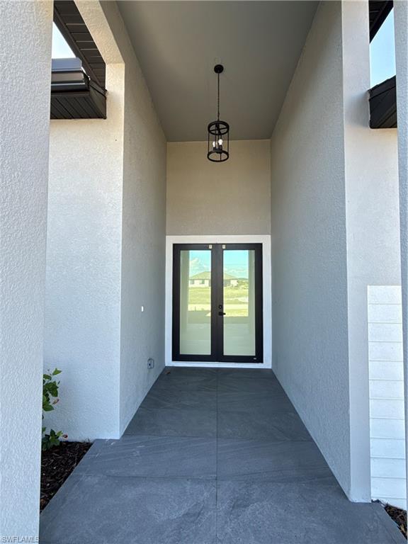 Entryway featuring a double door with dark frames, a high ceiling, and a dark-finished cylindrical pendant light
