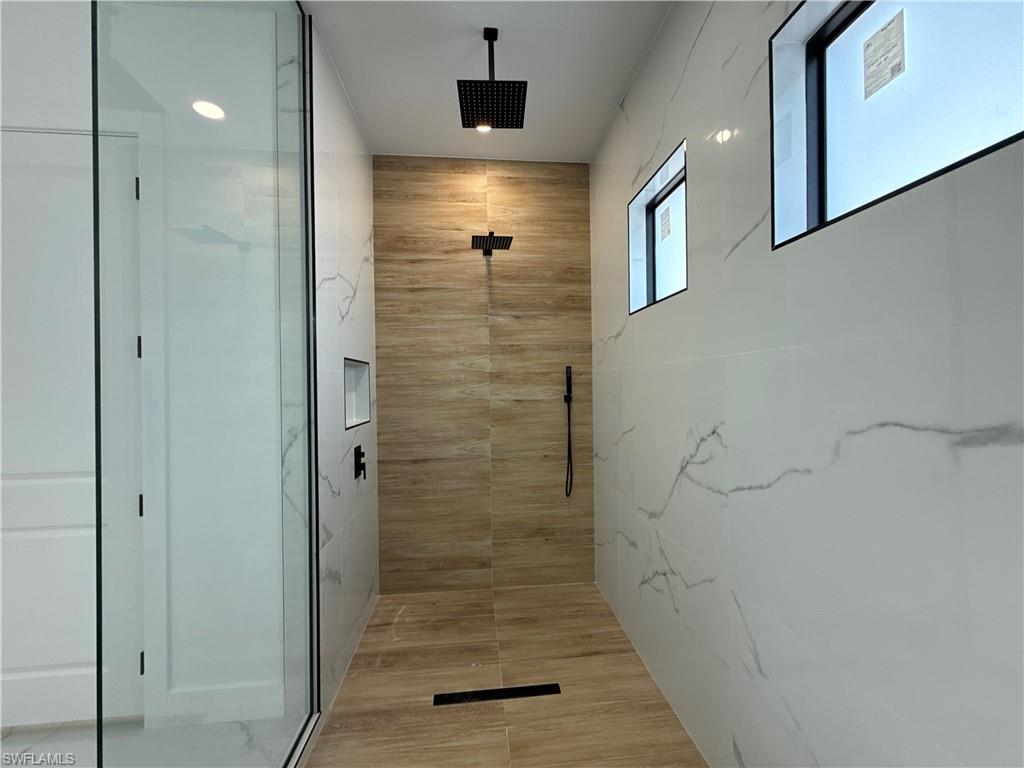 Walk-in shower with full-height tile, matte black fixtures, and a recessed niche