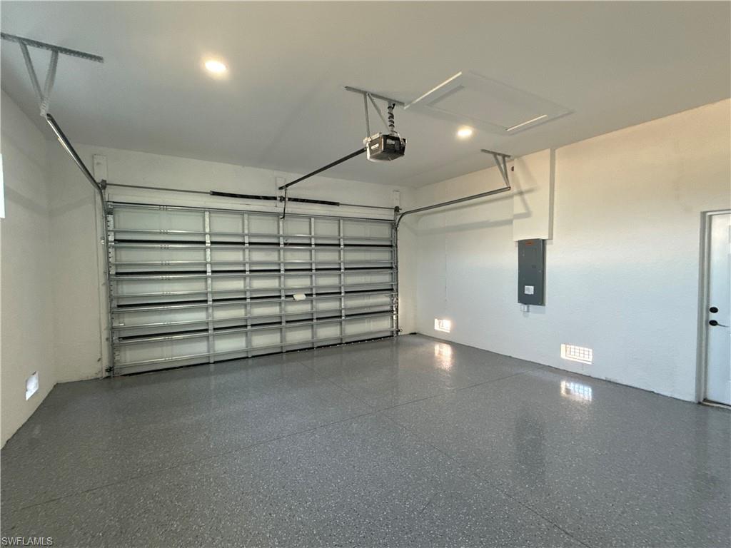 Spacious garage featuring a durable speckled epoxy floor, an automatic garage door opener, and recessed ceiling lighting