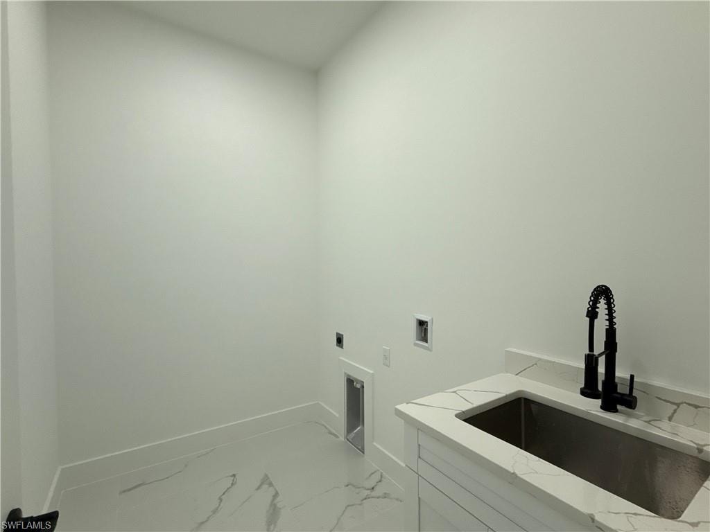 Utility sink with a matte black faucet, integrated into a white countertop, featuring white cabinetry