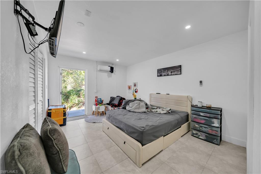 Spacious bedroom with neutral tile flooring, recessed ceiling lighting, and glass sliding doors opening to outdoor access