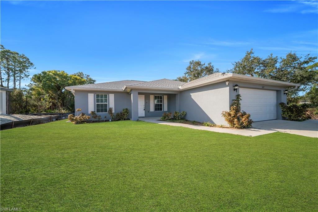 Gray stucco exterior with white window shutters and trim, featuring a white garage door, a covered entry, and a concrete driveway