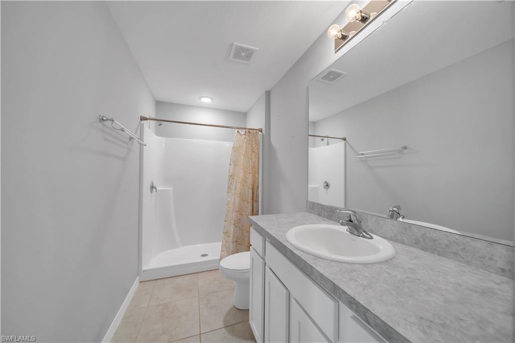 Bathroom featuring a white vanity with an integrated sink, a large mirror, a shower-tub combination, and tiled flooring