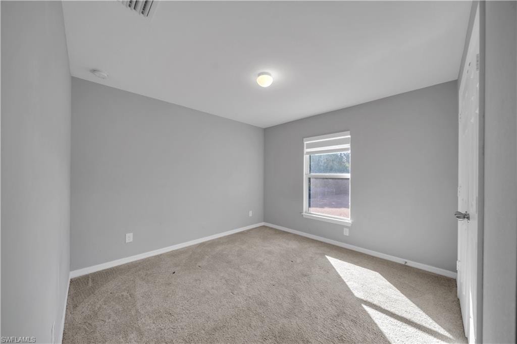 Neutral-toned carpet flooring, light gray wall paint, and a single window with white trim