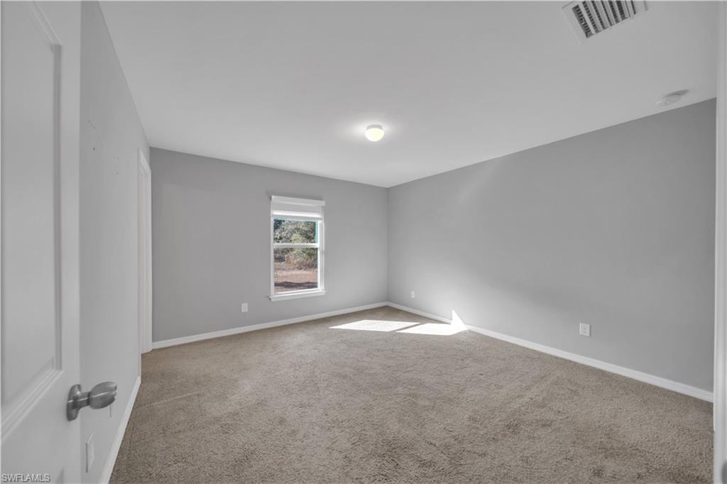 Neutral-toned carpet flooring, light gray wall paint, white window trim, and a flush mount ceiling light fixture