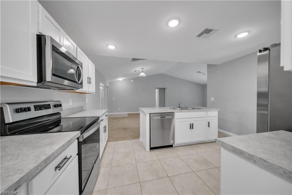 Kitchen featuring stainless steel appliances, white cabinetry, light-toned countertops, and recessed lighting