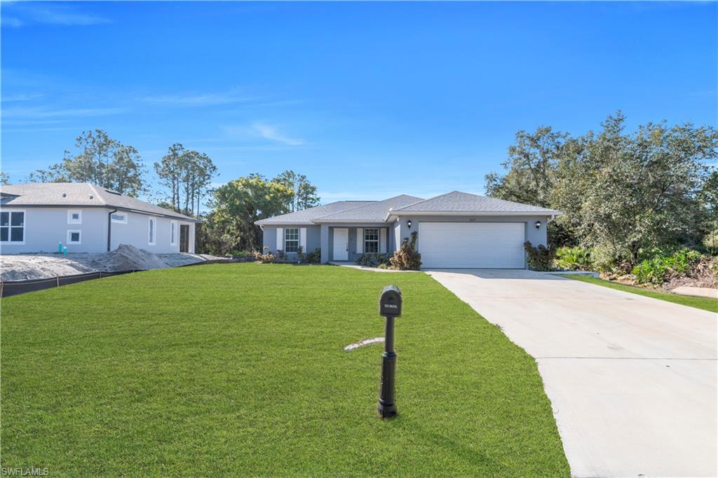 Expansive manicured lawn with mature landscaping and established trees, complemented by a concrete driveway leading to a single-story residence featuring a pitched roof design and attached garage