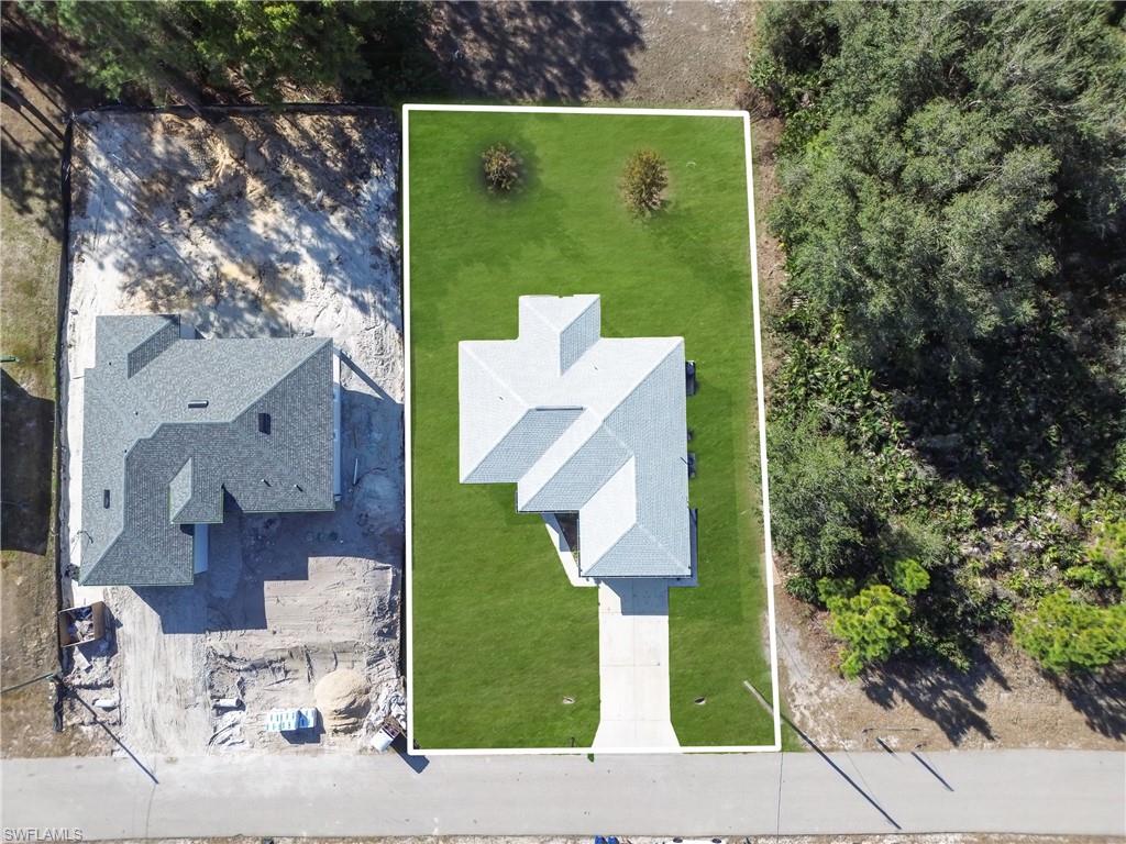 Newly constructed single-story residence featuring a light-toned shingle roof, green lawn, and a concrete driveway