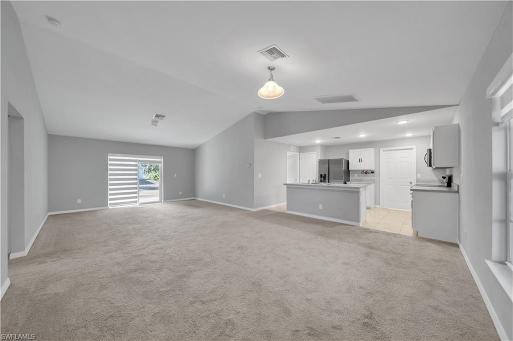 Open-concept living area featuring a kitchen with light-toned cabinetry, a stainless steel refrigerator, and a built-in microwave