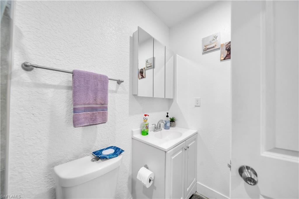 White vanity with integrated sink, chrome faucet, and mirrored medicine cabinet