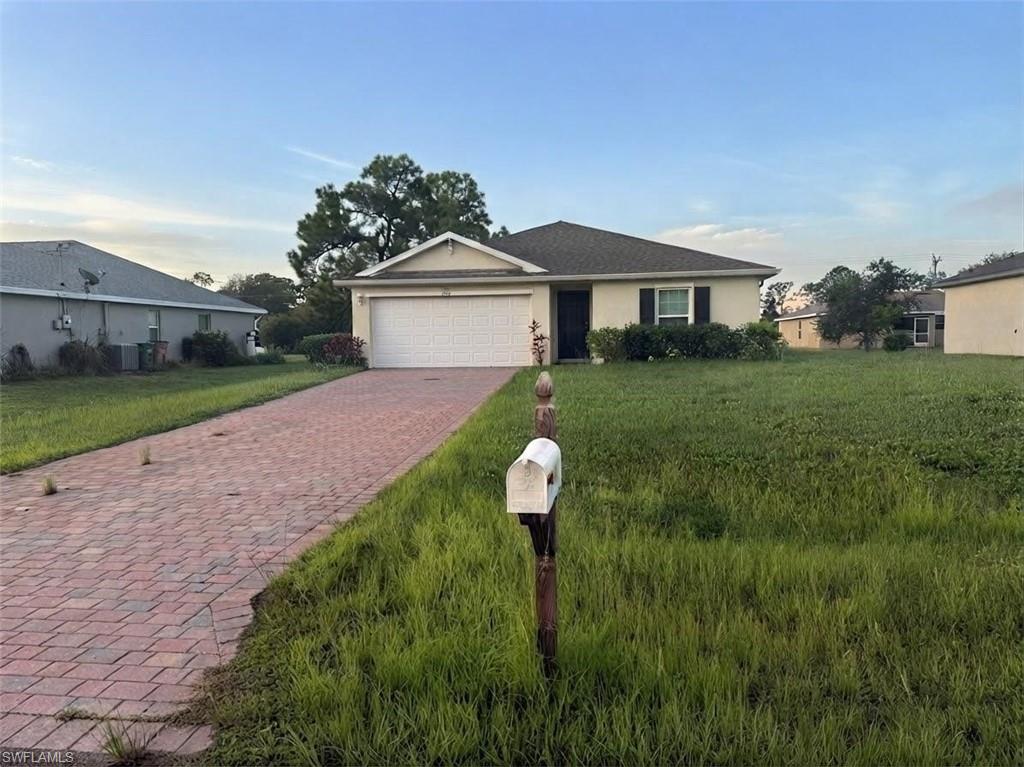 Single-story residence featuring a two-car garage, front entry, and red brick paver driveway