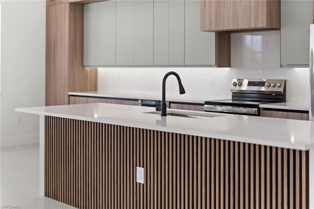 Kitchen island with slatted wood-finish paneling, white countertop, integrated sink, and matte black faucet