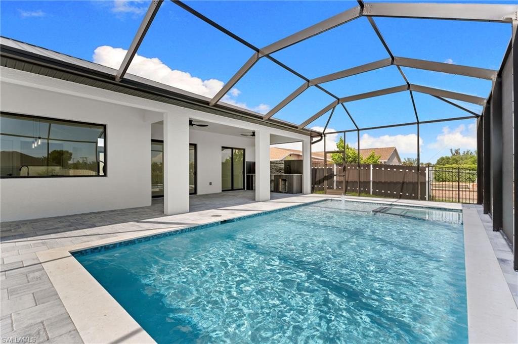 Screen-enclosed pool area featuring a rectangular pool, integrated spa, and paver decking