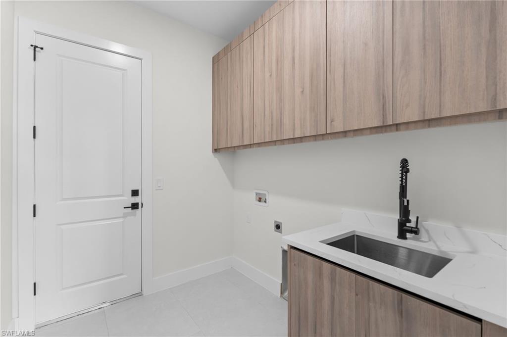 Built-in cabinetry with wood-finish doors, integrated sink, matte black faucet, white countertop, and white panel door with black hardware