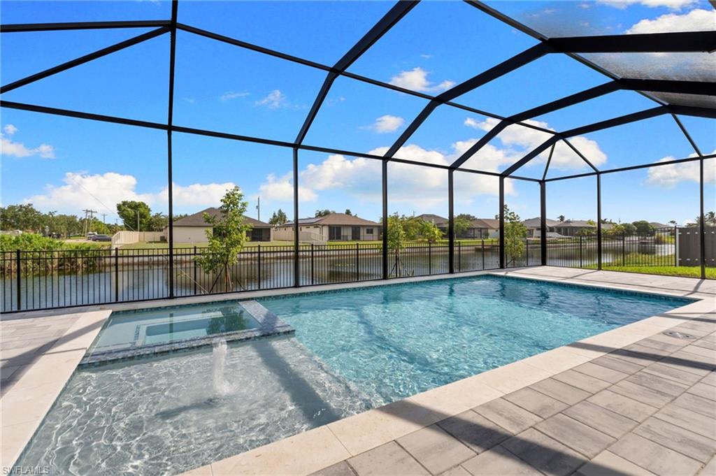 Screened lanai featuring a swimming pool, integrated spa, and expansive paver deck