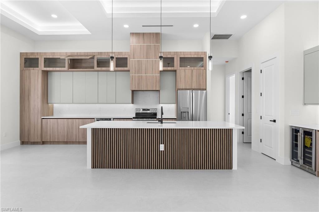 Kitchen featuring a central island with slatted wood paneling, white countertops, built-in stainless steel appliances, and integrated wood-finish cabinetry