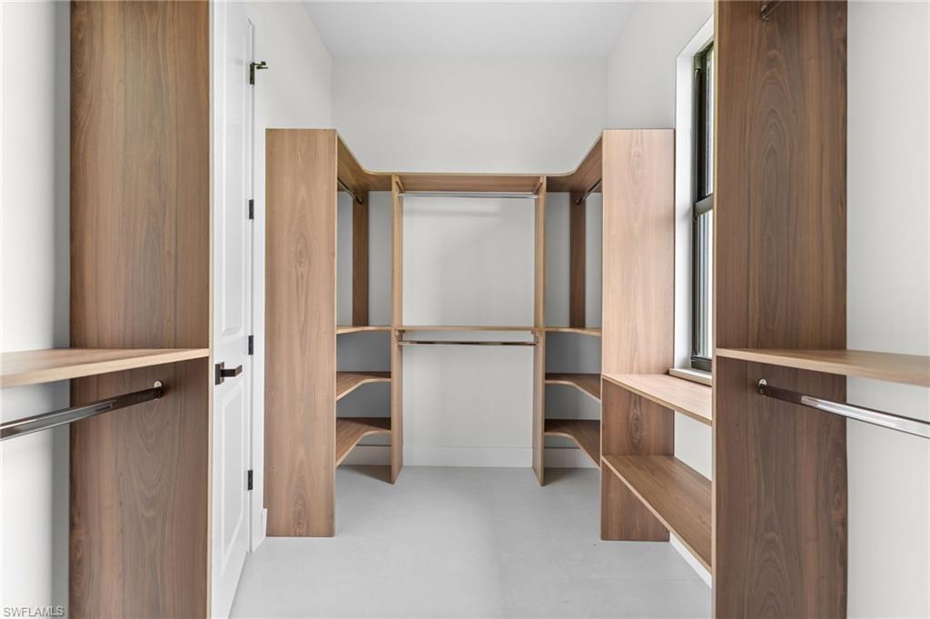 Custom closet system featuring wood-finish shelving, integrated hanging rods, and a window