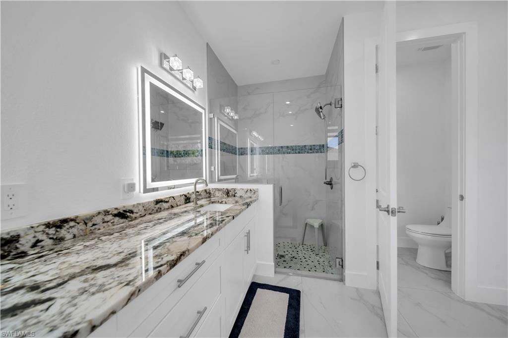 Dual vanity with stone countertop, back-lit mirrors, and integrated sinks