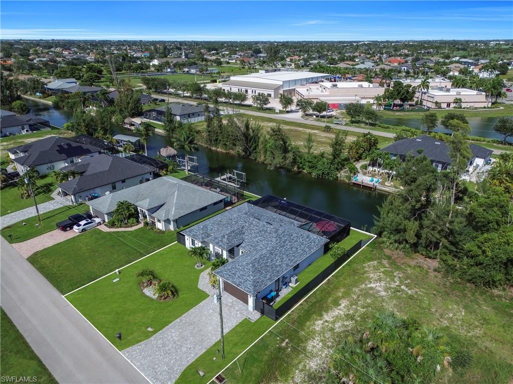 Waterfront property featuring a screened enclosure, a paver driveway, and a well-maintained lawn