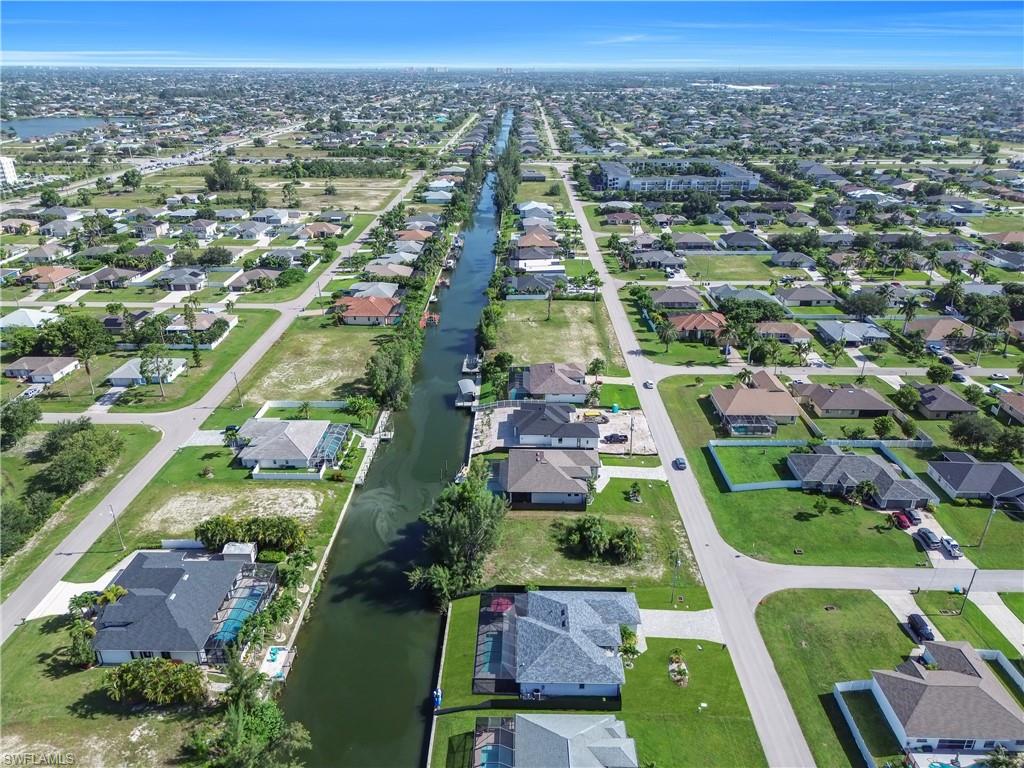 Aerial perspective showcasing a residential area with a prominent waterway, multiple properties with private docks, and a grid street layout