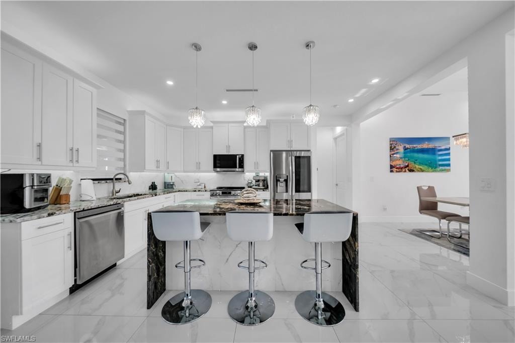 Spacious kitchen with white cabinetry and integrated stainless steel appliances