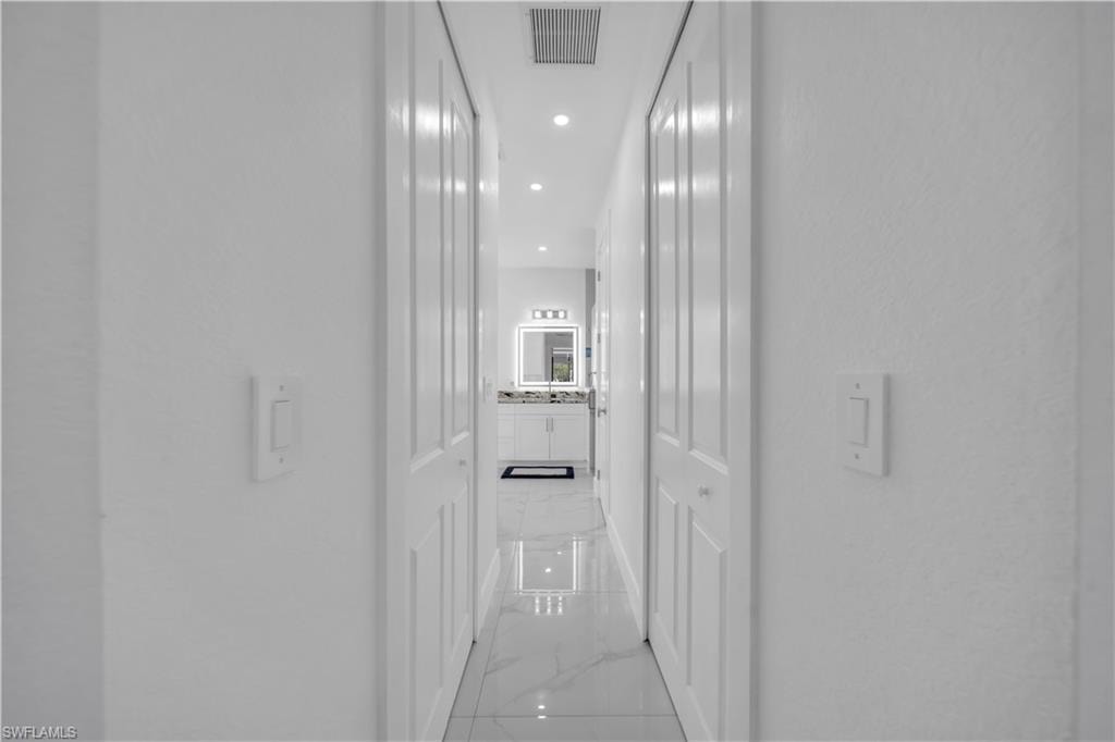 Hallway with white panel doors, recessed lighting, and polished tile flooring