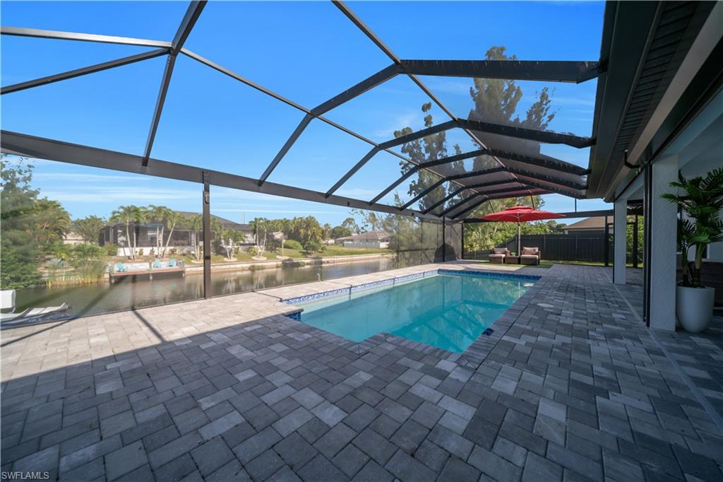 Screened enclosure with a rectangular swimming pool, paver patio, and canal frontage