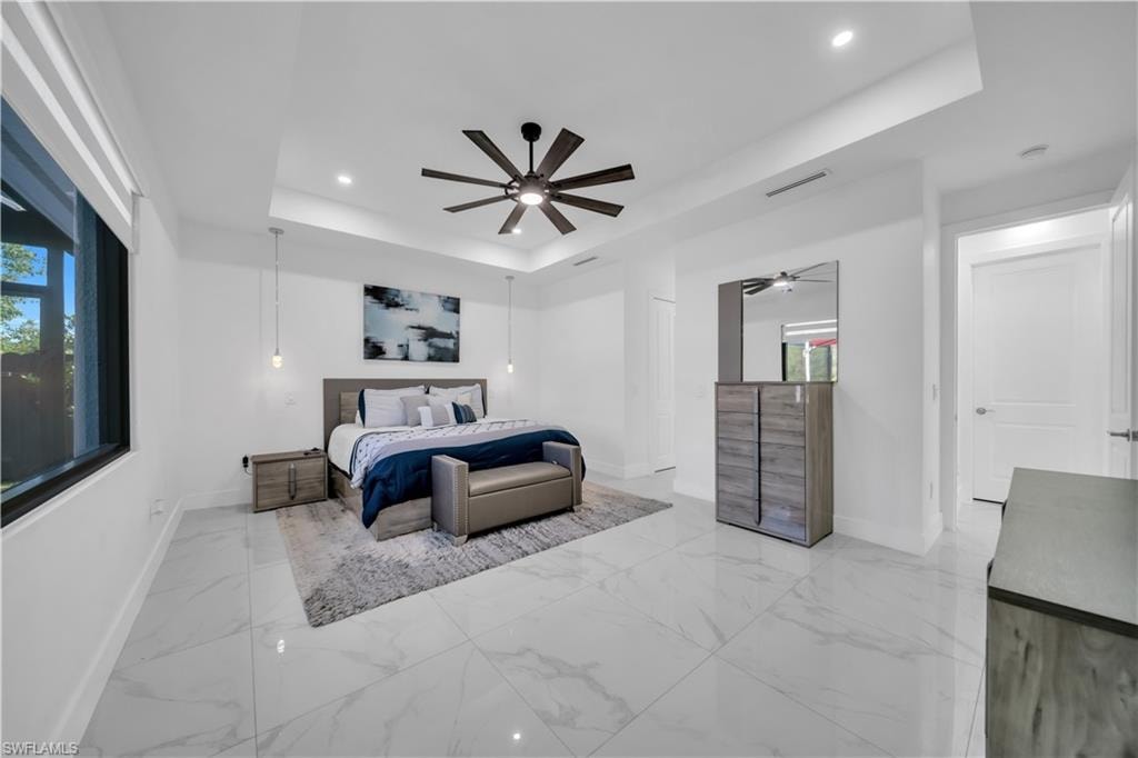 Spacious primary bedroom showcasing polished marble-finish flooring, recessed ceiling lighting, and a modern ceiling fan with integrated light fixture