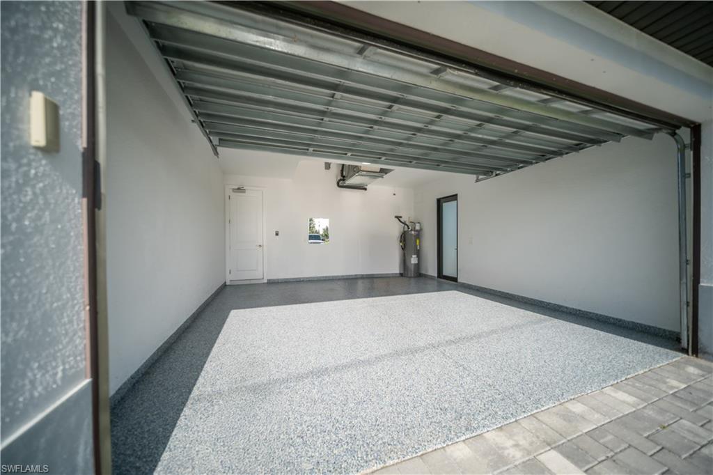 Expansive garage featuring a speckled epoxy flooring, white painted walls, and a visible garage door mechanism