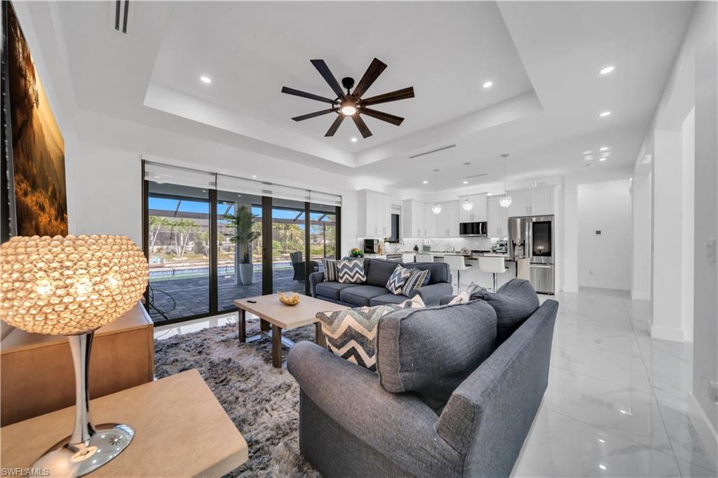 Recessed lighting, tray ceiling, and a ceiling fan enhance the living space