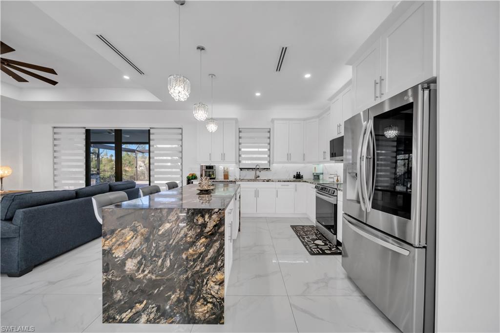 Gourmet kitchen featuring a large kitchen island with a stone finish, stainless steel appliances, and white cabinetry