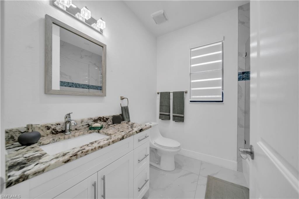 White shaker-style vanity with under-mount sink and stone countertop