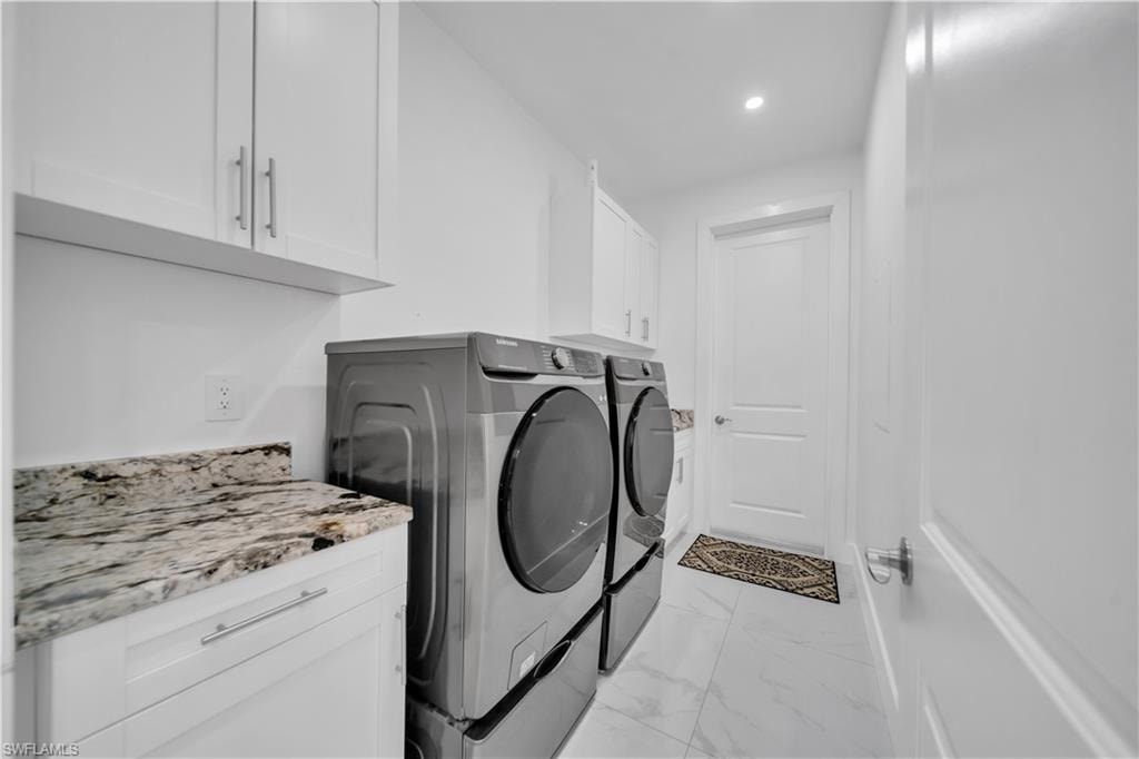 White shaker cabinetry, stone-finish countertops, recessed lighting, and large format tile flooring
