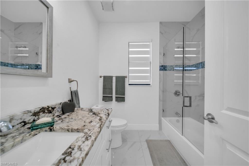 Vanity with granite countertop, integrated sink, and white cabinetry