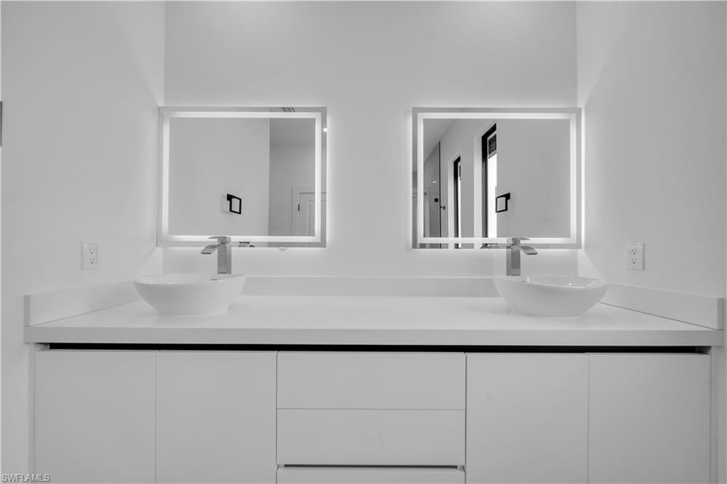 Recessed lighting illuminating the white built-in shelving, drawers, and hanging rods
