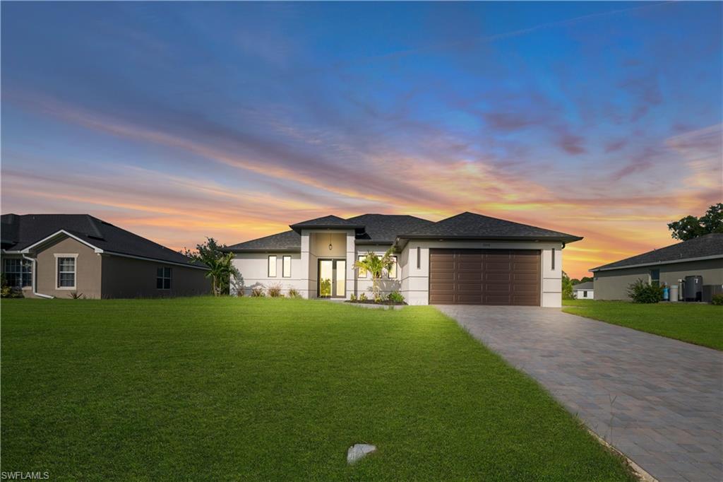 Contemporary exterior with a dark shingle roof, a two-car garage, a paver driveway, and a manicured lawn