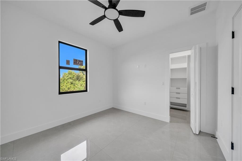 Recessed lighting, ceiling fan, three vertical windows, and light gray tile flooring